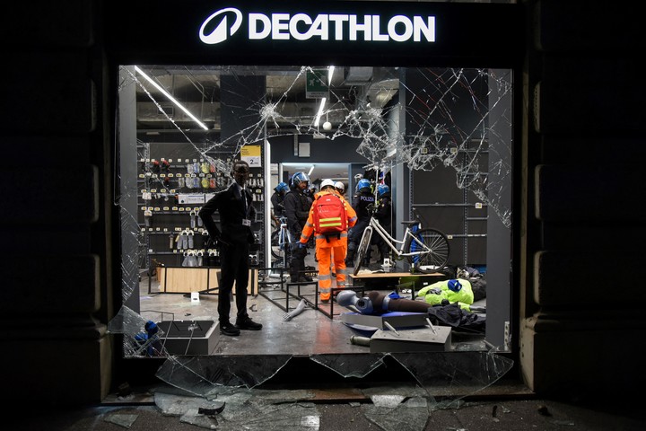 Agentes de policía permanecen dentro de una tienda de artículos deportivos Decathlon, tras los cristales rotos, durante las protestas en Milán. Foto Reuters /Stringer